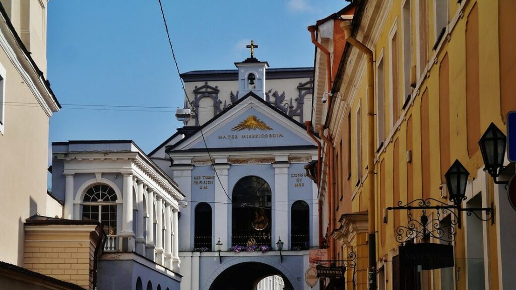 Porte de l'Aurore et sa chapelle blanche surplombant la rue, entre des façades colorées de Vilnius