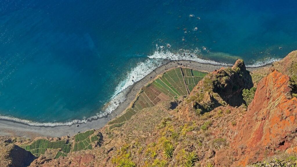 Falaise du Cabo Girão plongeant dans l'océan, avec des terrasses cultivées au pied et la mer turquoise