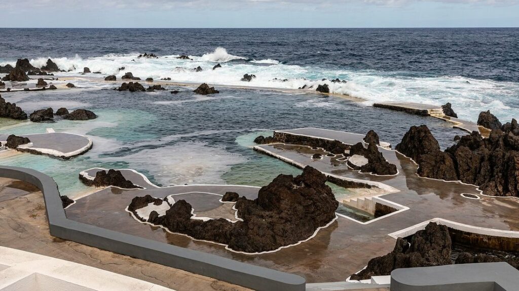 Bassins de lave aménagés au bord de l'océan à Porto Moniz, avec des vagues qui éclaboussent les rochers noirs