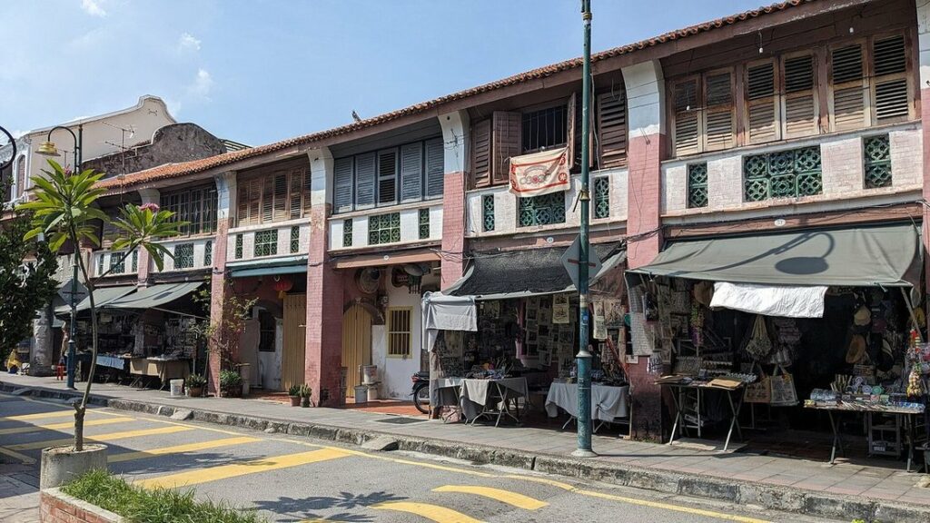 Rangée de maisons-boutiques anciennes aux auvents colorés le long d'une rue ensoleillée