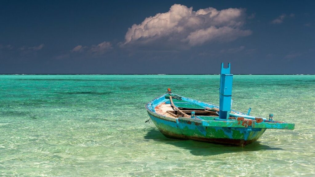 Vieux bateau en bois à la coque bleue posé dans une eau turquoise peu profonde, au bord de l'île de Thoddoo