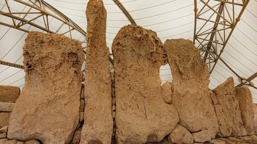 Grands blocs de pierre dressés du temple mégalithique de Hagar Qim, abrités sous une toiture de protection