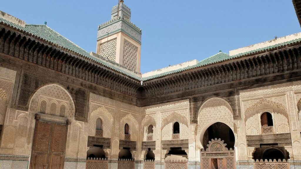 Cour intérieure de la medersa Bou Inania avec ses galeries de bois sculpté et un minaret au fond