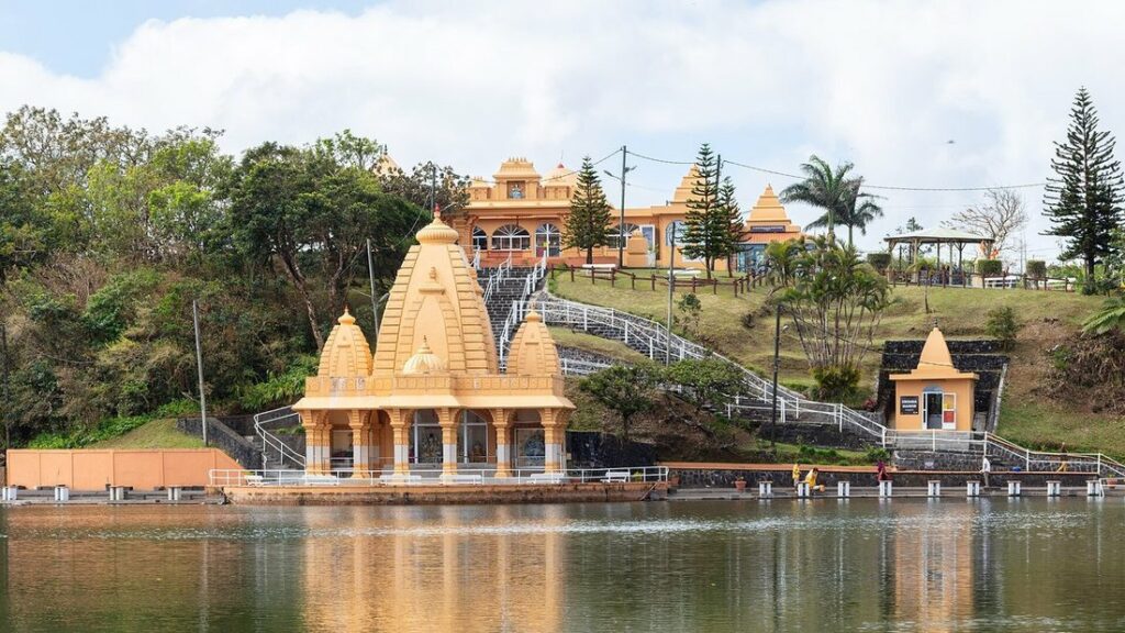 Temple hindou aux tours orangées au bord d'un lac, avec son reflet dans l'eau