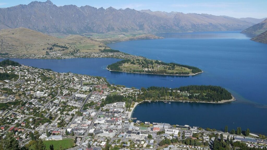 Vue aérienne de la ville de Queenstown au bord d'un grand lac bleu, avec des montagnes en arrière-plan