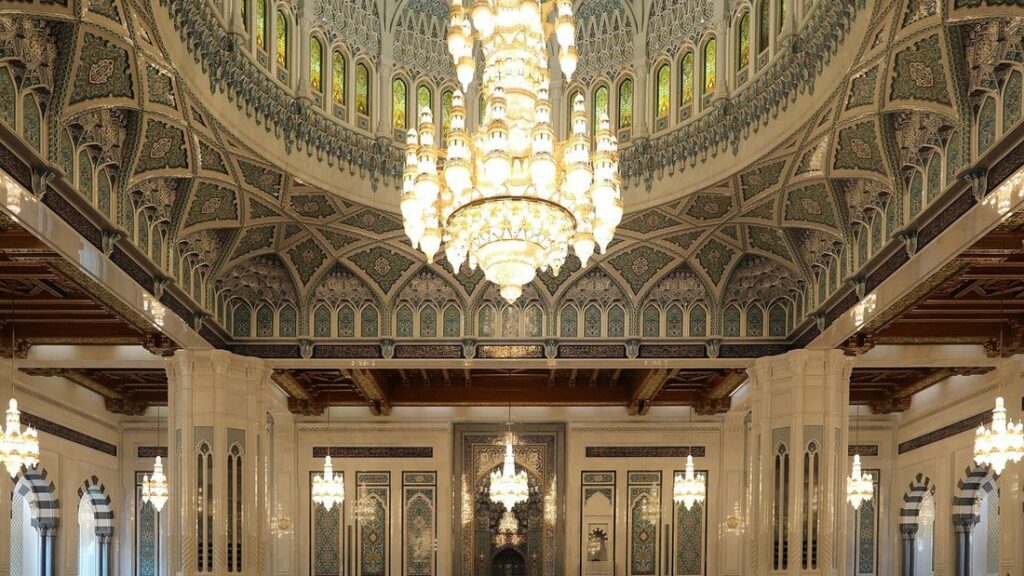 Grand lustre en cristal sous une coupole décorée à l'intérieur de la mosquée du Sultan Qaboos
