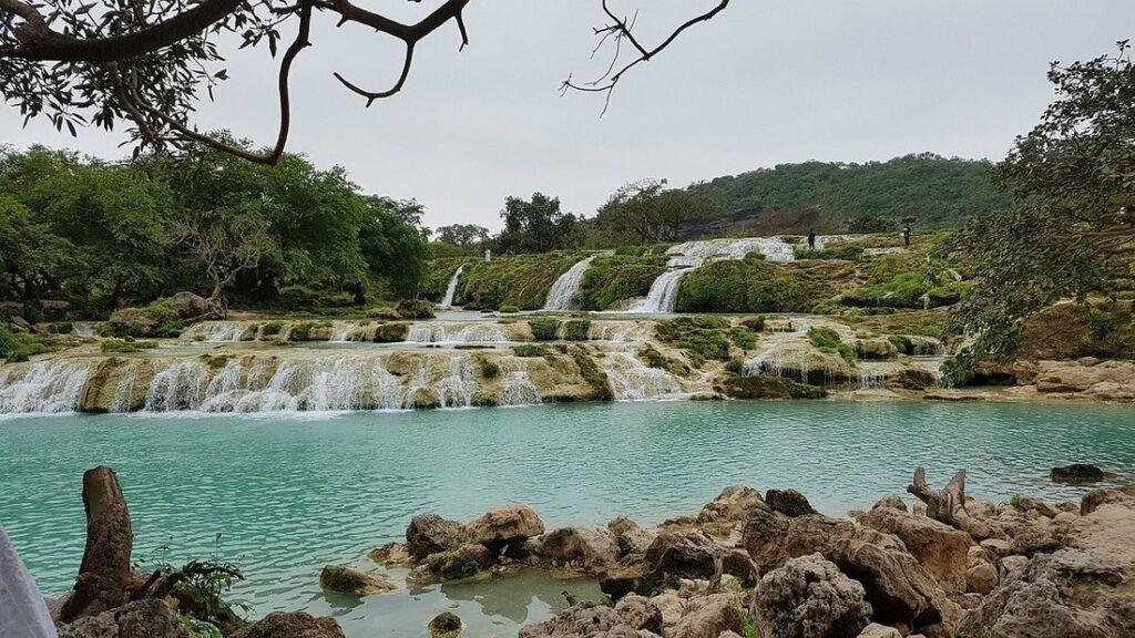 Cascades étagées et bassins turquoise entourés de végétation verte à Wadi Darbat