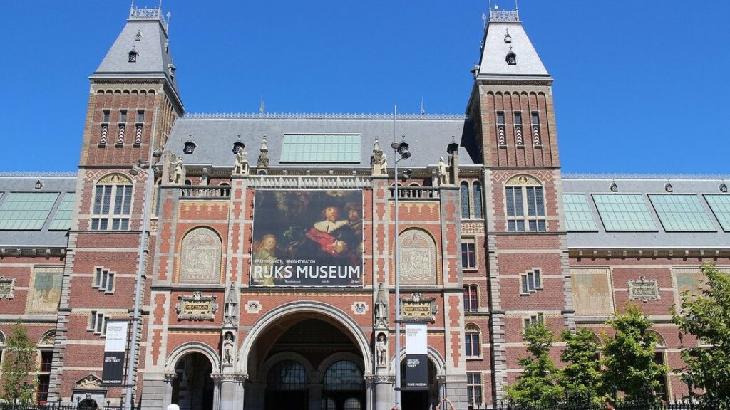 Façade de brique rouge du Rijksmuseum, à deux tours et grande arche d'entrée, sous un ciel bleu