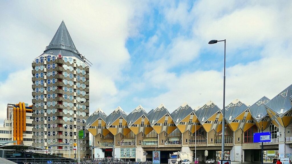 Maisons cubiques jaunes alignées au pied d'une tour d'habitation en forme de crayon