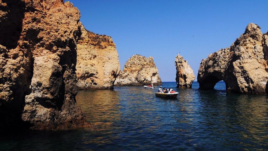 Falaises ocre et arches rocheuses de la Ponta da Piedade près de Lagos, avec une petite embarcation sur l'eau