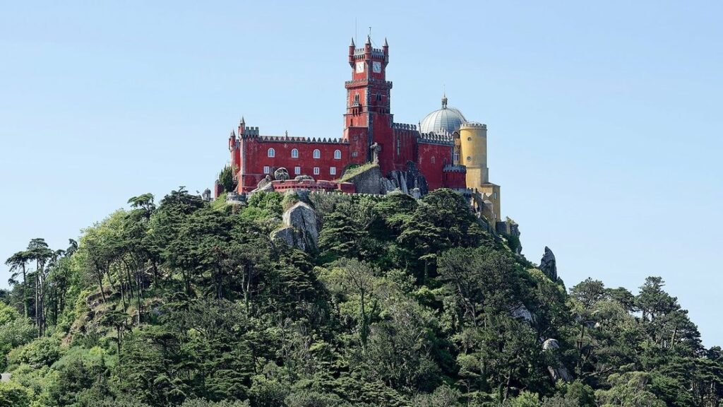 Palais de Pena aux murs rouges et jaunes, perché au sommet d'une colline boisée près de Sintra