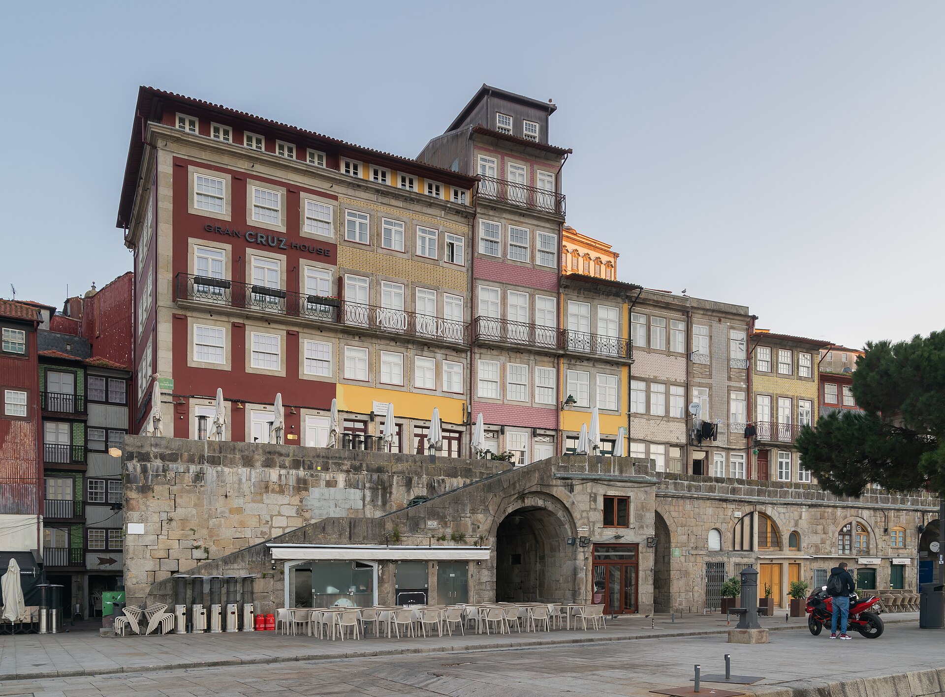 Façades colorées de la Ribeira à Porto, au-dessus d'une arche de pierre et de terrasses de café sur la place