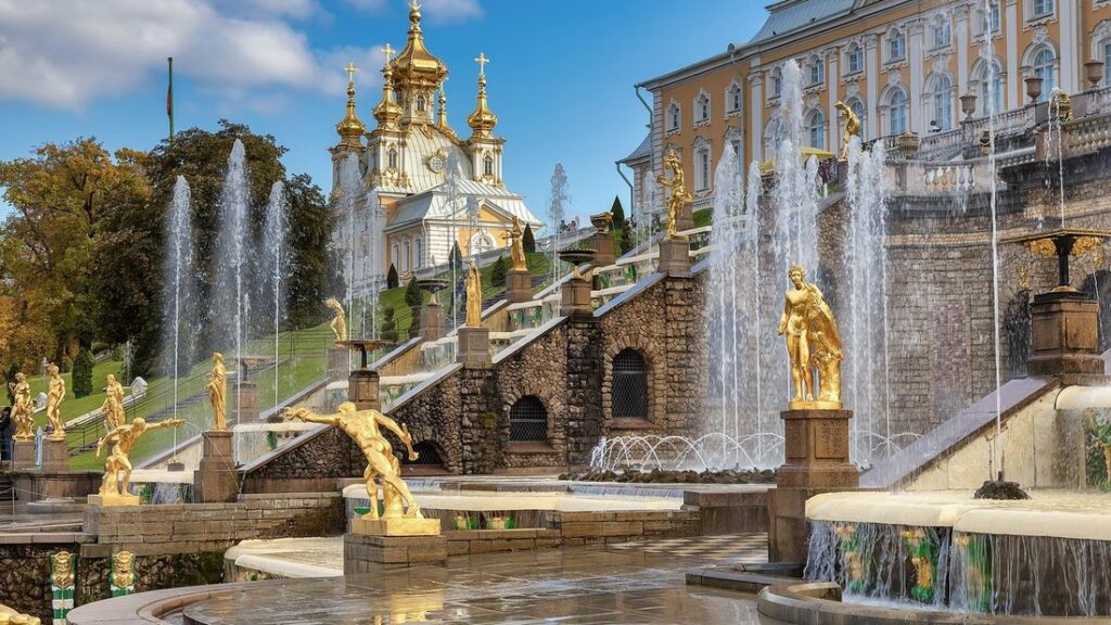 Palais de Peterhof, fontaines et statues dorées de la Grande cascade, avec une chapelle aux coupoles dorées à gauche
