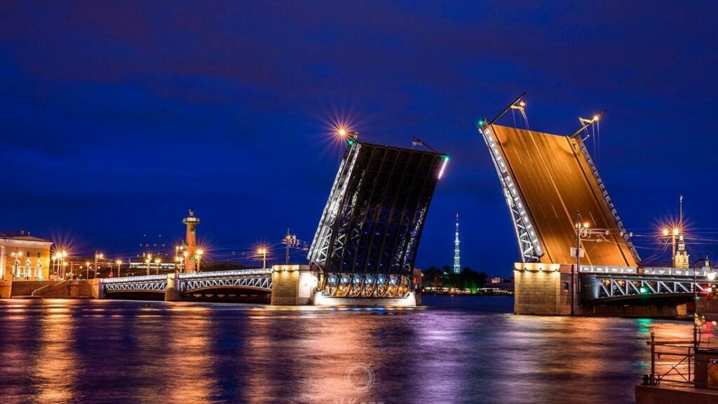 Pont levé aux deux tabliers dressés et éclairés au-dessus de la Neva, sous un ciel bleu nuit