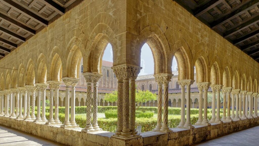 Galerie à arcades et colonnettes jumelées du cloître de la cathédrale de Monreale, éclairée par le soleil