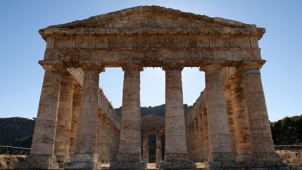 Le temple dorique de Ségeste vu de face, avec ses colonnes de pierre dorée et le ciel bleu entre elles