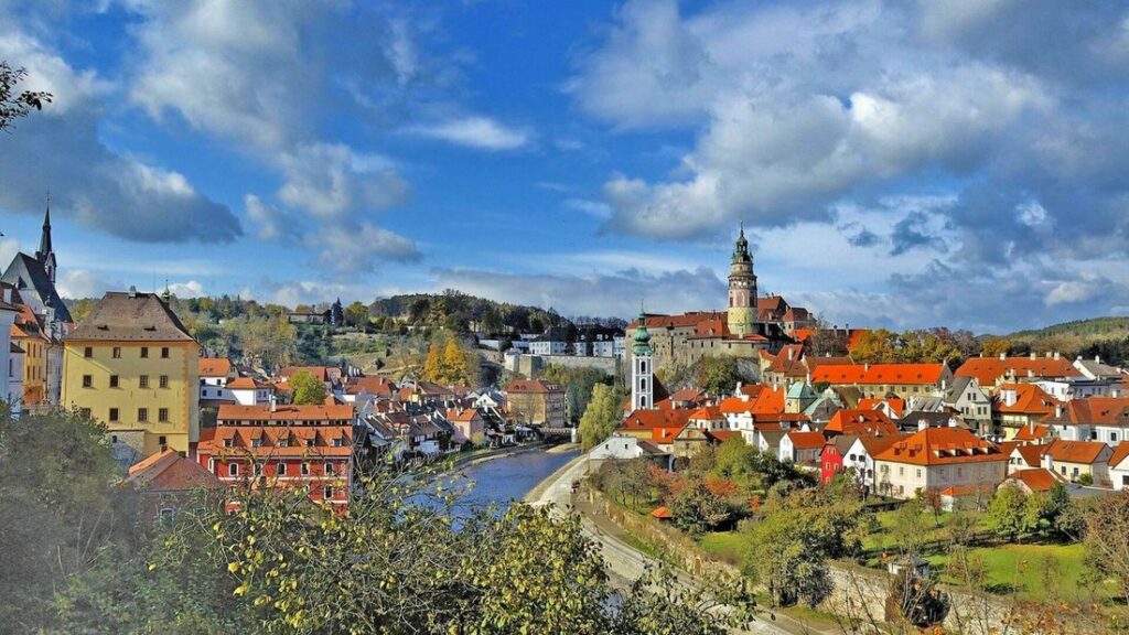 Panorama de Český Krumlov, toits orangés, boucle de la Vltava et tour du château sous un ciel bleu nuageux