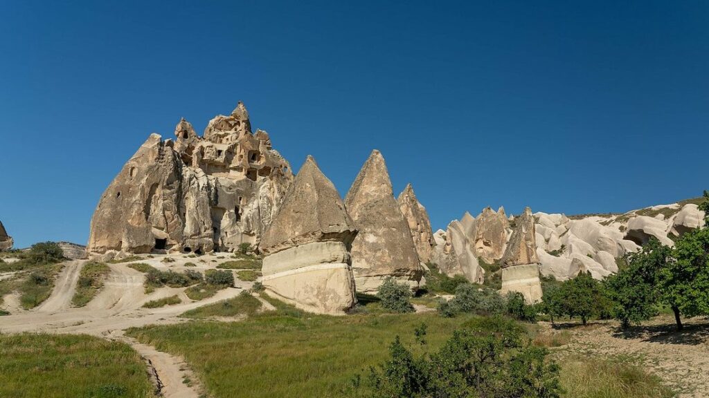 Cheminées de fées rocheuses de Cappadoce au-dessus d'une vallée verte, sous un ciel bleu