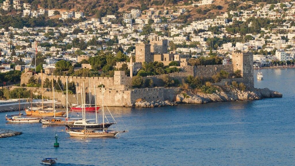 Le château de Bodrum au bord de l'eau, avec des voiliers dans le port et la ville blanche derrière