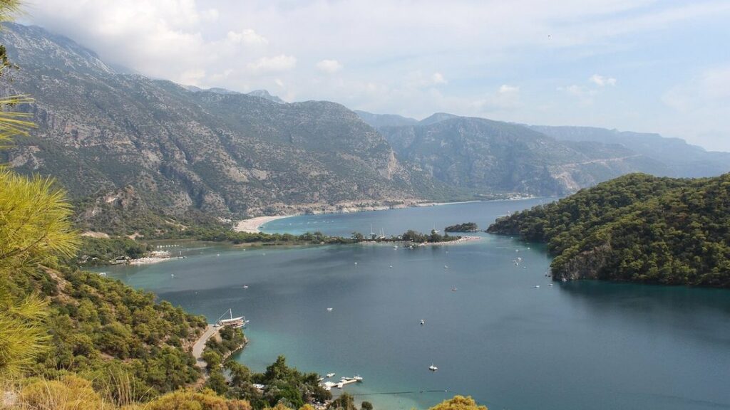 Lagune d'Ölüdeniz vue des hauteurs, eau calme, bande de sable clair et montagnes boisées