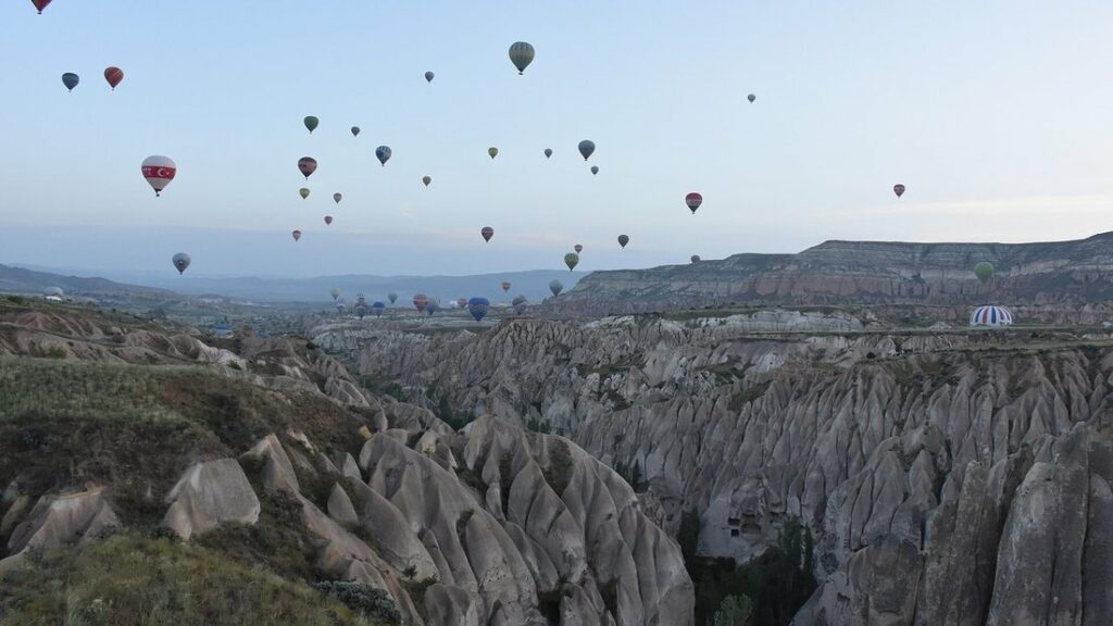 De nombreuses montgolfières dans le ciel au-dessus de vallées aux reliefs de roche claire, près de Göreme