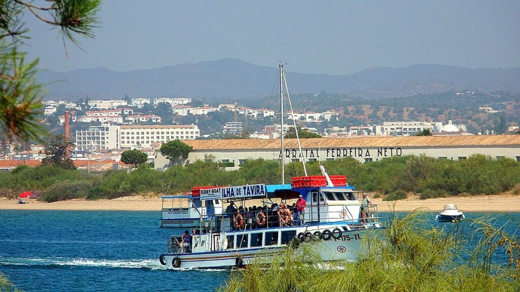 Bateau « Ferry-boat Ilha de Tavira » traversant la lagune devant la rive de Tavira et les collines de l'Algarve