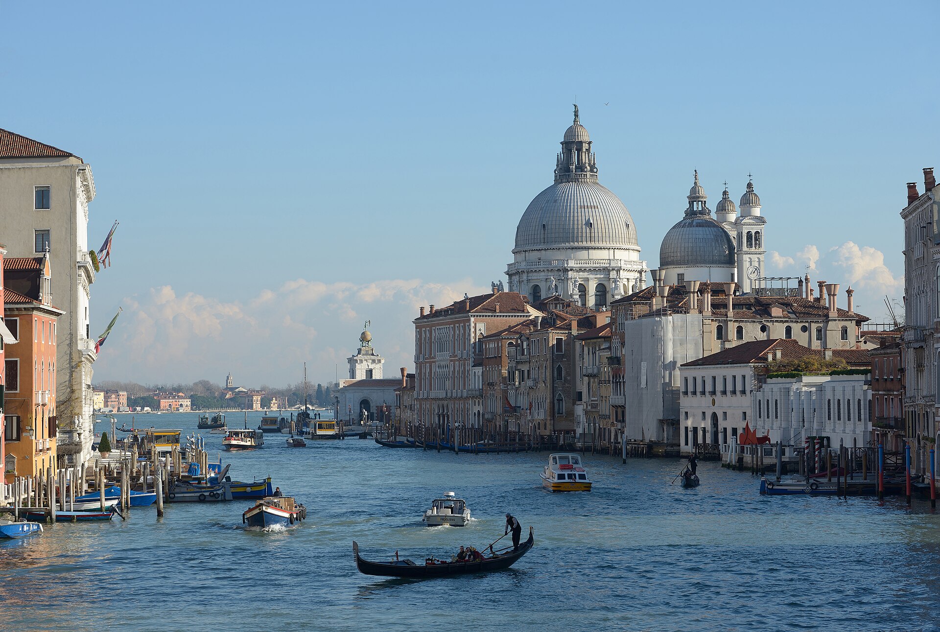 Gondole sur le Grand Canal de Venise, devant la coupole grise de la basilique Santa Maria della Salute sous un ciel bleu