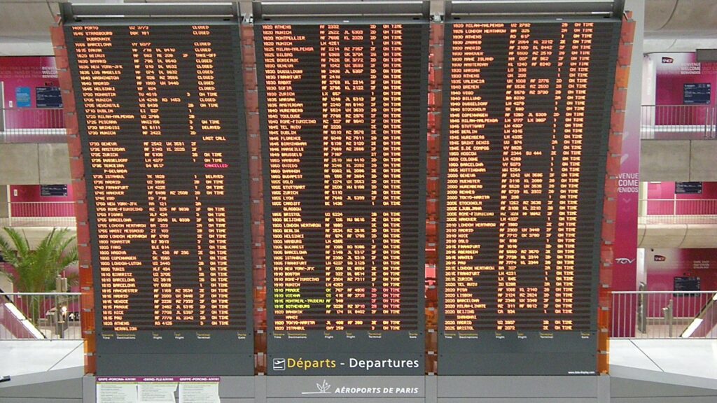 Trois grands panneaux d'affichage des départs de l'aéroport Paris-Charles de Gaulle, avec heures, destinations et statuts des vols