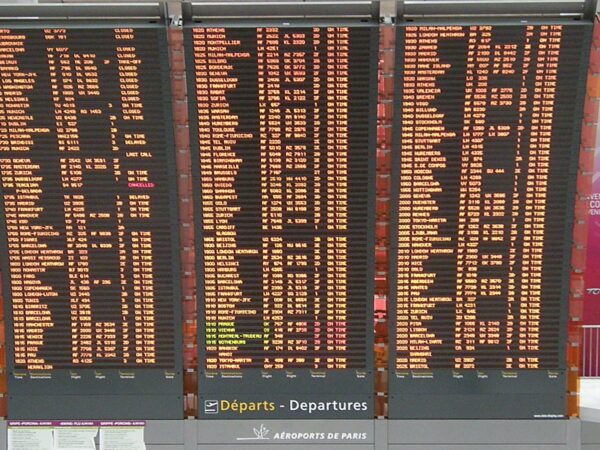 Trois grands panneaux d'affichage des départs de l'aéroport Paris-Charles de Gaulle, avec heures, destinations et statuts des vols