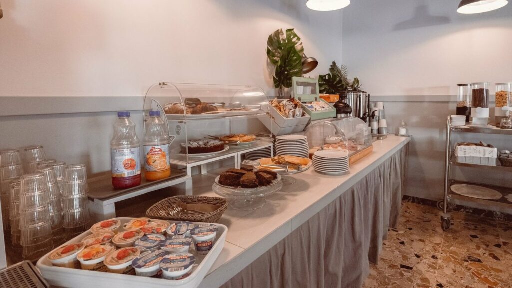 Buffet de petit-déjeuner avec viennoiseries, gâteaux, pots de yaourt, bouteilles de jus et distributeurs de céréales