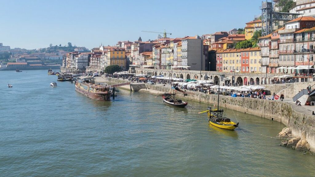 Quai de la Ribeira à Porto vu du pont, maisons colorées, terrasses et bateau jaune sur le Douro