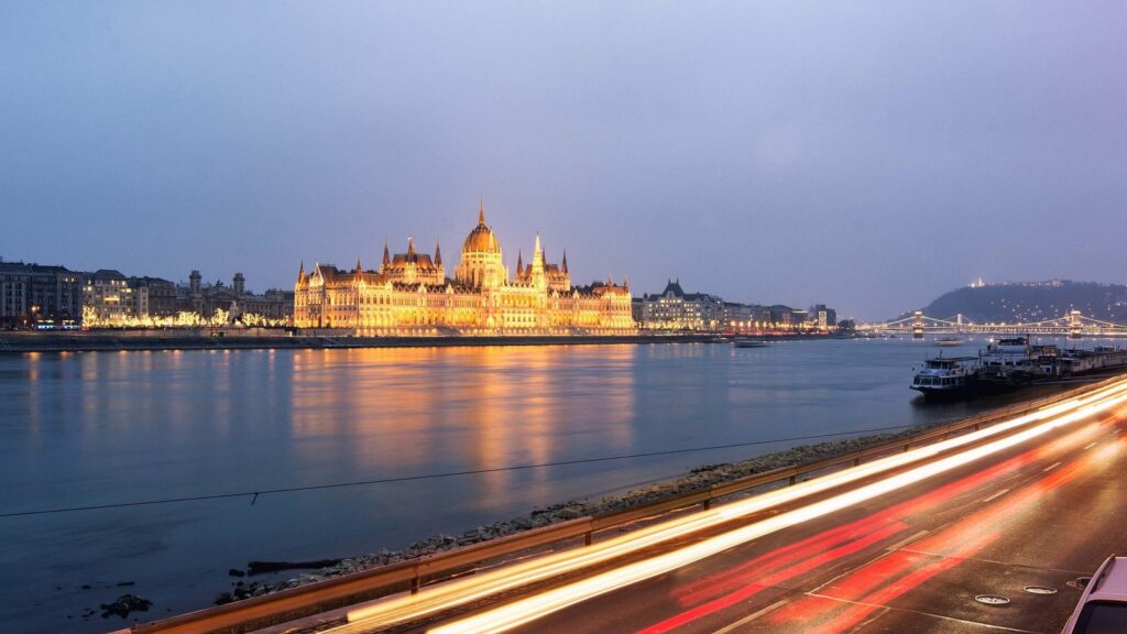 Le Parlement de Budapest éclairé au crépuscule, face au Danube qui reflète ses lumières dorées