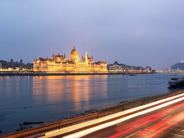 Le Parlement de Budapest éclairé au crépuscule, face au Danube qui reflète ses lumières dorées