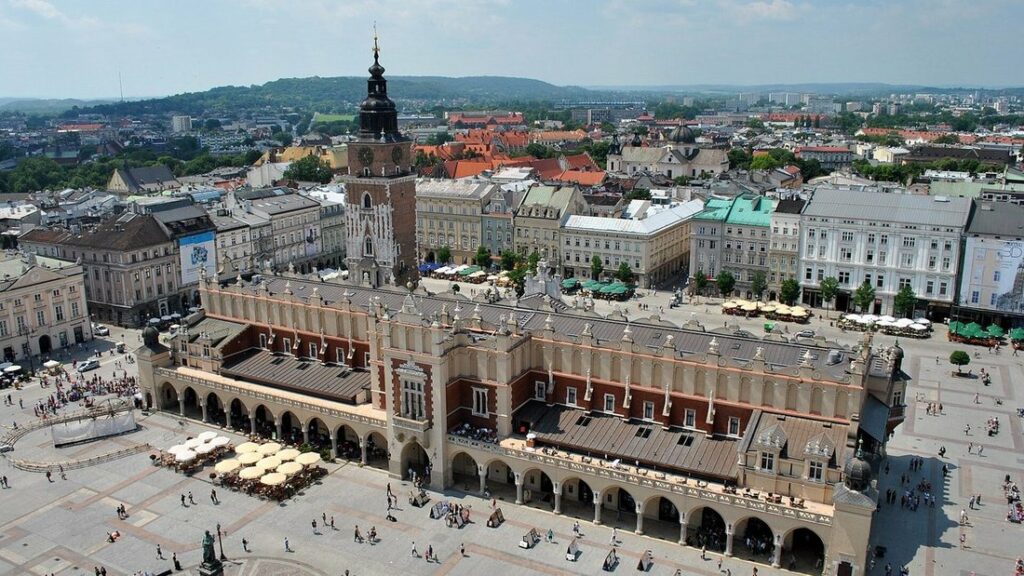 Vue plongeante sur la halle aux draps au milieu de la grand-place de Cracovie, bordée de façades claires et de toits