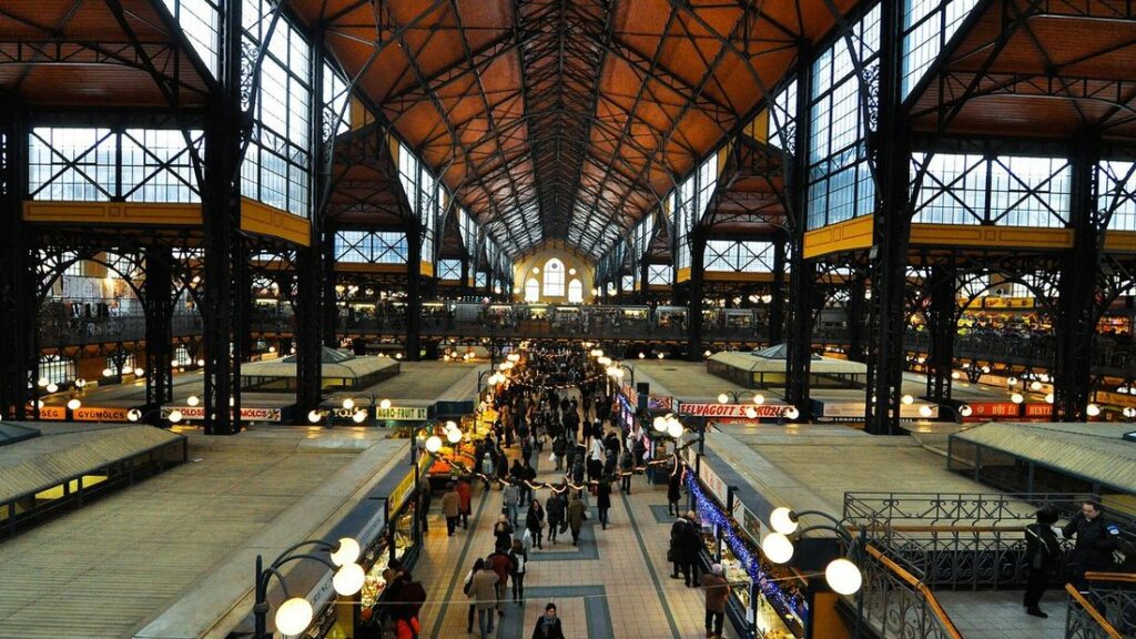 Intérieur de la halle centrale de Budapest, avec sa charpente métallique, son allée centrale et ses étals éclairés