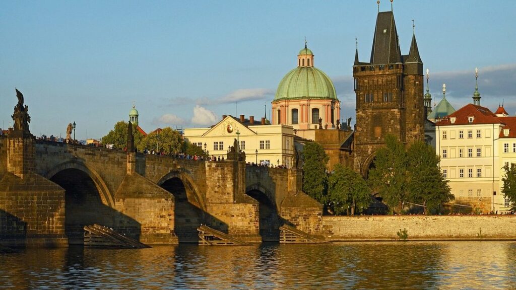Le pont Charles et la tour de la Vieille-Ville au bord de la Vltava, avec une coupole verte et des façades jaunes derrière