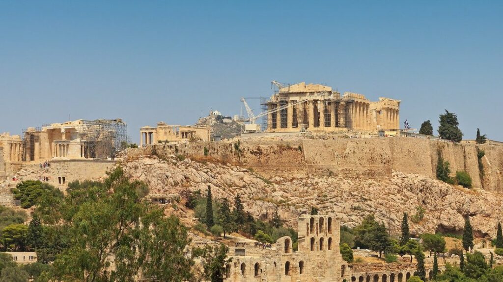 L'Acropole d'Athènes vue depuis la colline de Philopappos, avec le Parthénon au sommet et des arbres au premier plan