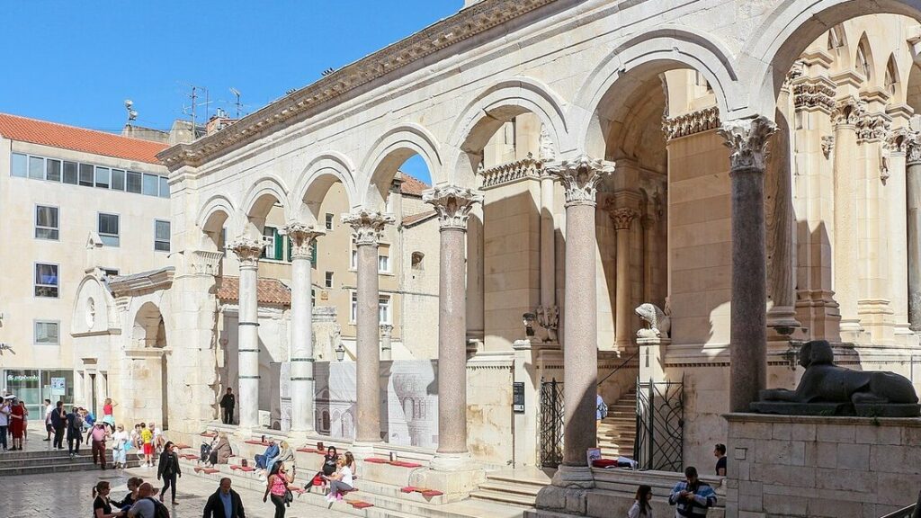 Colonnade à arcades en pierre claire du péristyle du palais de Dioclétien à Split, avec passants et sphinx noir