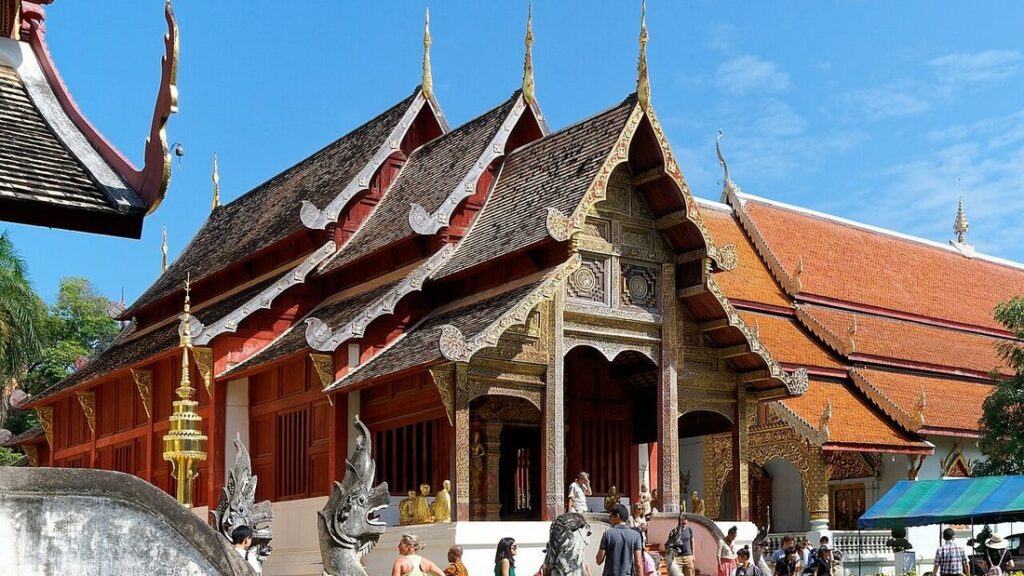 Temple Wat Phra Singh à Chiang Mai, aux toits étagés en bois sombre, aux façades rouges et pignons dorés