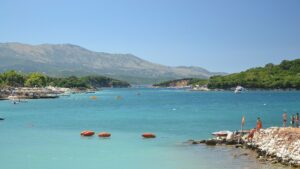 Baie turquoise de Ksamil, en Albanie, avec des îlots boisés et une chaîne de montagnes à l'horizon