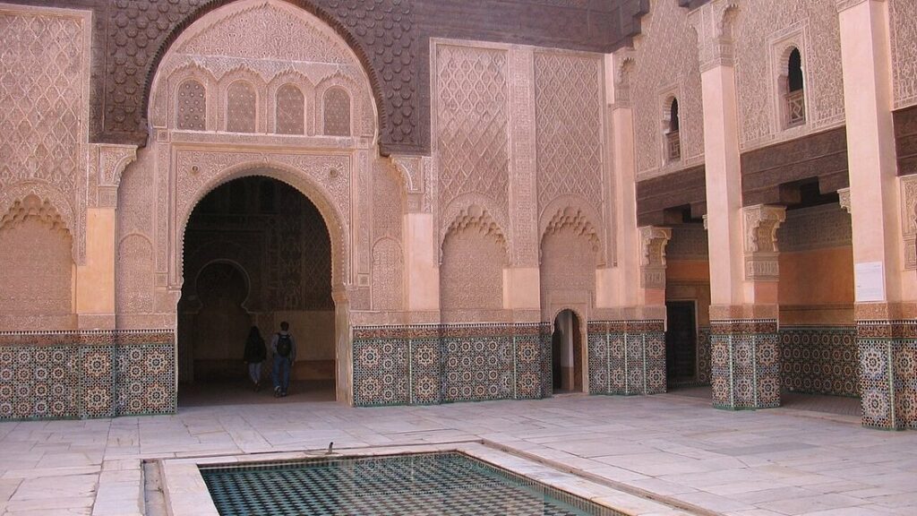 Cour de la médersa Ben Youssef à Marrakech avec bassin carrelé, murs en stuc sculpté et soubassements en zelliges