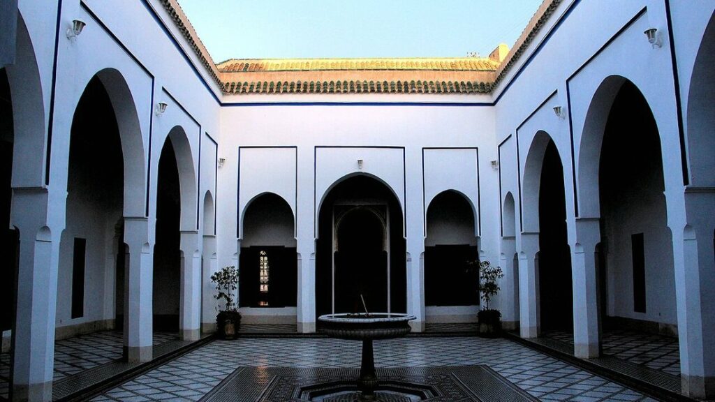 Cour intérieure aux murs blancs, arcs en fer à cheval, fontaine et sol en mosaïque, au palais de la Bahia