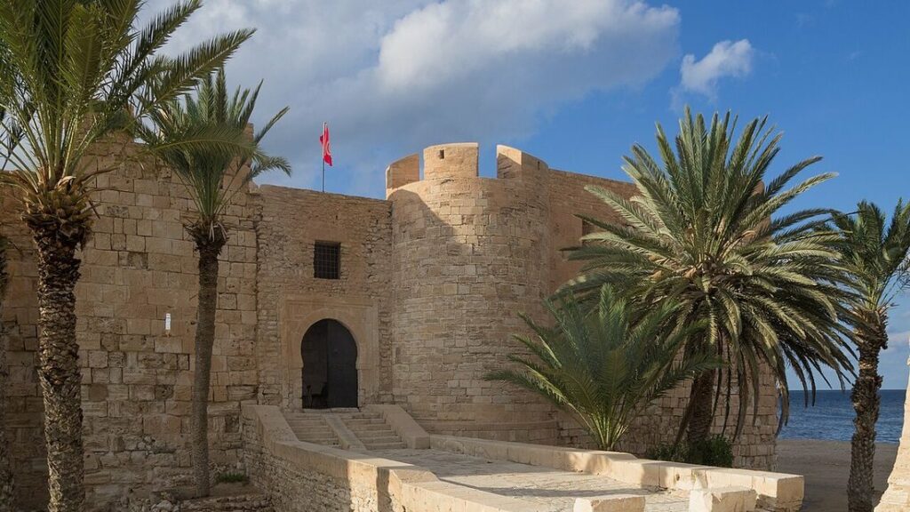 Mur de pierre ocre d'un fort à tour crénelée, entouré de palmiers, à Houmt Souk sur l'île de Djerba