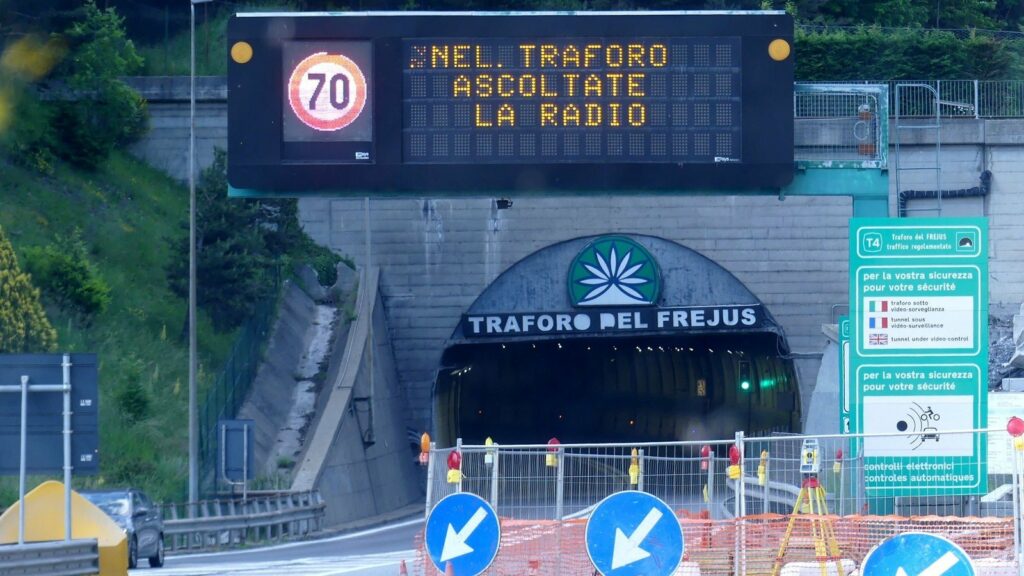 Entrée italienne du tunnel routier du Fréjus, avec un panneau lumineux affichant 70 et la consigne d'écouter la radio