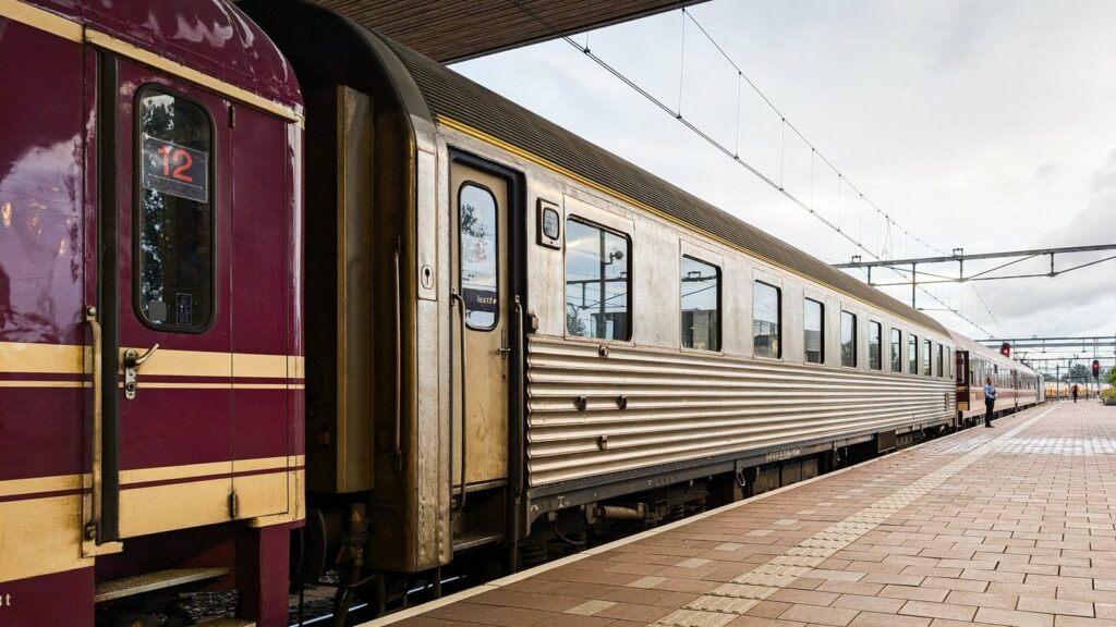 Voitures-lits d'un train de nuit, l'une bordeaux et or, l'autre en inox cannelé, le long d'un quai de la gare de Rotterdam Centraal