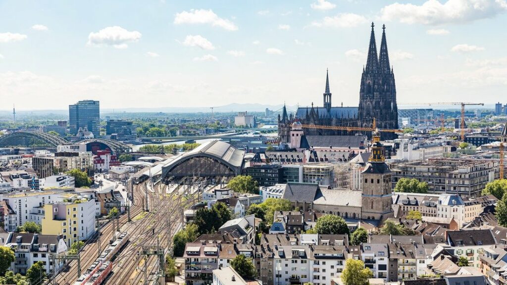 Vue d'en haut sur la gare centrale de Cologne, ses voies et la cathédrale aux deux flèches sombres