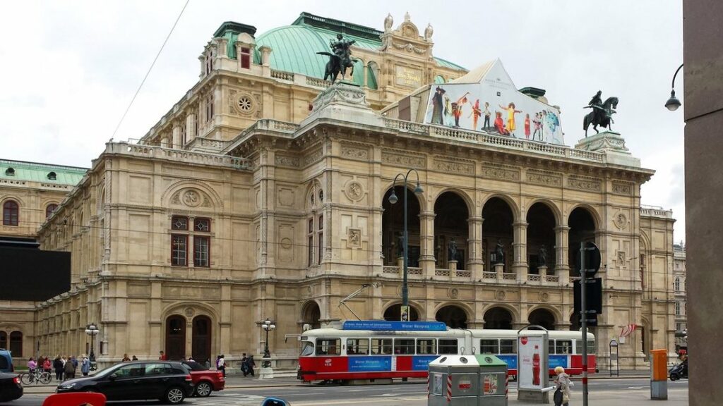 L'Opéra d'État de Vienne et un tramway rouge et blanc qui passe devant sa façade, sur le Ring