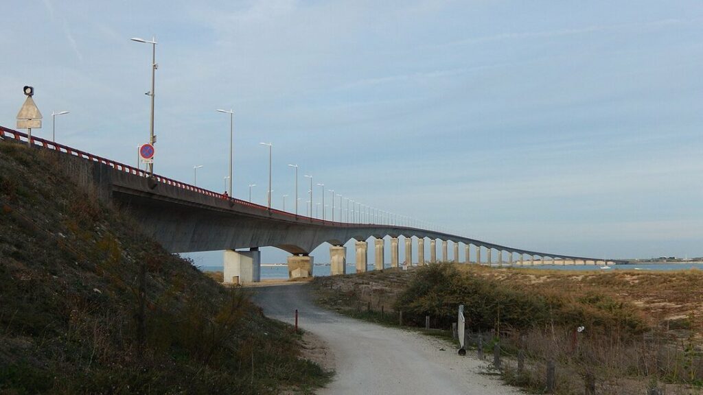 Pont de l'île de Ré, long viaduc de béton aux piles régulières au-dessus de l'eau, vu depuis la rive