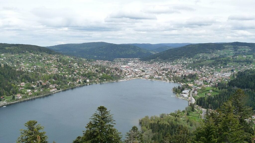 Vue plongeante sur le lac de Gérardmer, la ville au fond et les collines boisées des Vosges